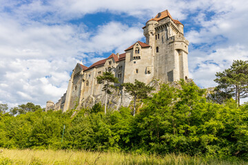 Historic castle in Austria surrounded by picturesque countryside and lush alpine scenery, presenting a timeless European architectural landmark beneath a dramatic sky. The elegant fortress © Yuliia
