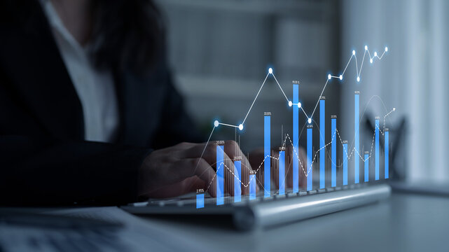A business professional engages with a laptop displaying interactive financial data, showcasing a growth graph and performance metrics in a modern office environment. Scalp