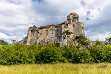 Historic castle in Austria surrounded by picturesque countryside and lush alpine scenery, presenting a timeless European architectural landmark beneath a dramatic sky. The elegant fortress © Yuliia
