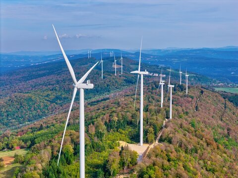 Aerial view of Parc eolien du Lomont wind turbines situated on a forested ridge with rolling hills and autumn foliage in Vyt-les-Belvoir, Bourgogne-Franche-Comte, France.