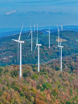 Aerial view of Parc eolien du Lomont with wind turbines rising above the dense autumn forest in Vyt-les-Belvoir, Bourgogne-Franche-Comte, France.