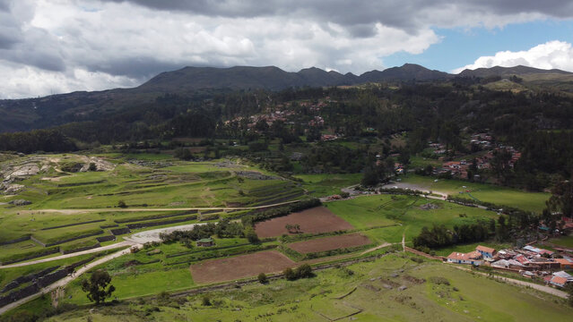 Aerial view of the ancient Incan ruins of Sacsayhuaman with terraced fields, green hills, and rural settlements in Cusco, Cusco, Peru.