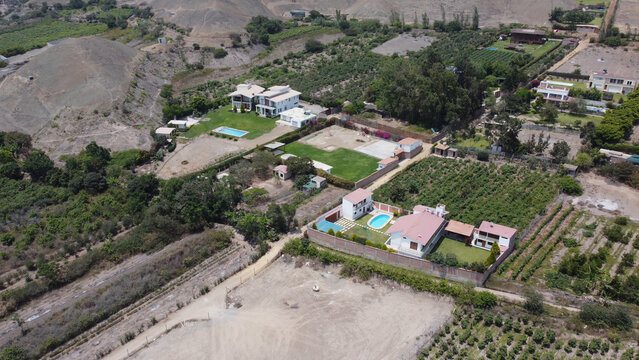 Aerial view of Azpitia featuring residential houses with swimming pools, lush gardens, and surrounding agricultural fields in Santa Cruz de Flores, Gobierno Regional de, Peru.