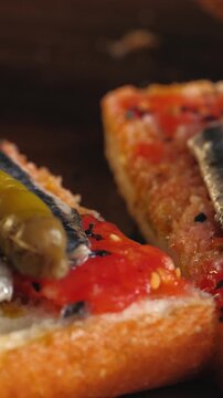 Pan con tomate with anchovies and guindilla pepper, close up of classic Spanish tapas gilda with marinated boquerones on tomato bread, Spanish cuisine bar snack