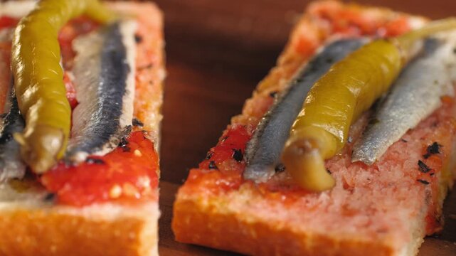 Pan con tomate with anchovies and guindilla pepper, close up of classic Spanish tapas gilda with marinated boquerones on tomato bread, Spanish cuisine bar snack