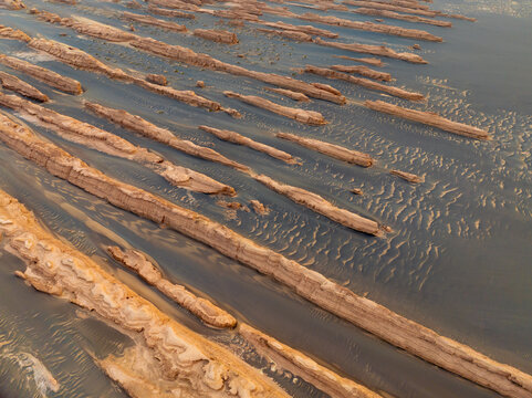 Aerial view of Geological Park Yadan Scenic Spot featuring unique wind-eroded rock formations and rippled sand dunes under golden light in Jiu Quan Shi, Gan Su Sheng, China.