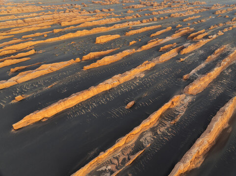 Aerial view of Yadan National Geological Park featuring unique wind-eroded rock formations and dark desert sands in Jiuquan, Gansu, China.