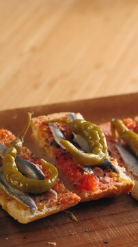 Pan con tomate with anchovies and guindilla pepper, close up of classic Spanish tapas gilda with marinated boquerones on tomato bread, Spanish cuisine bar snack