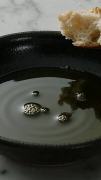 Vertical video: Pouring oil from top into iron pan creating ripples on marble top to fry