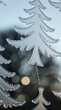 Vertical video: Shifting camera revealing frosted tree decals on pane, droplet chain showing detail
