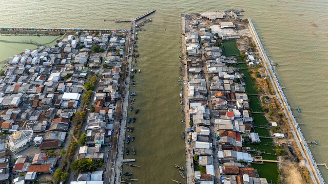 Aerial view of Pelabuhan Tanjung Emas showing the canal lined with traditional fishing boats and dense residential buildings in Semarang Utara, Central Java, Indonesia.