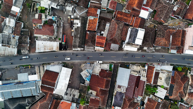 Aerial view of Ciwidey with a busy road cutting through dense residential rooftops and urban infrastructure in Bandung, West Java, Indonesia.