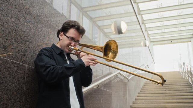 Portrait of Caucasian young adult playing trombone on urban in slow motion. Footage suited for music education, arts advertising and cultural campaigns