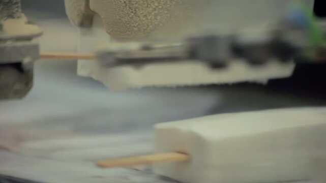 Closeup vanilla popsicles moving belt. Frosty gripper holding ice cream bars.