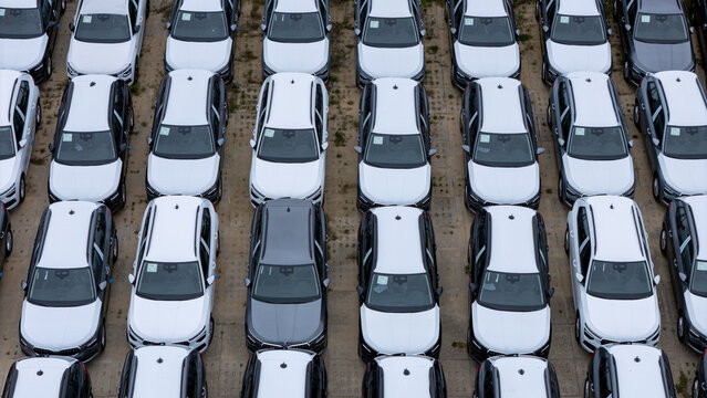Aerial view of rows of new white cars and one grey car parked in a large lot in Gdansk, Poland.