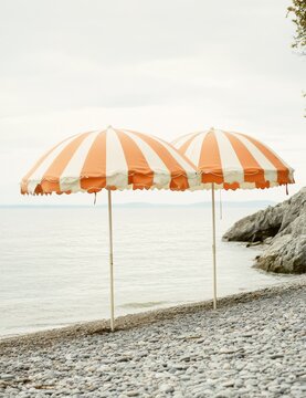 Orange and white striped vintage beach umbrellas on seaside coast