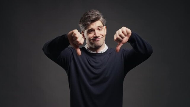 Handsome Man Giving Thumbs Down Dislike With Disapproving Look. Negative feedback, rejection, poor results, product review, disagreement
