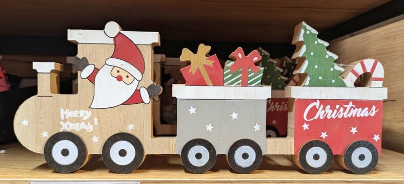 Decoraci&oacute;n de Navidad. Vista de cerca de un tren de madera, con Santa Claus y el texto Merry Xmas en la locomotora y regalos de Navidad en los vagones, en estante de tienda 