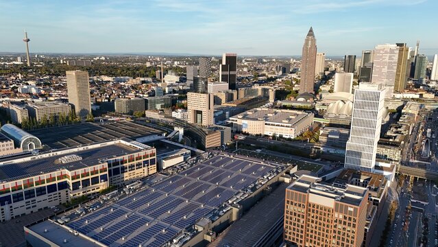 Aerial view of the Frankfurt am Main skyline featuring modern skyscrapers, the Messe Frankfurt exhibition center with solar panels, and urban infrastructure in Frankfurt, Hessen, Germany.