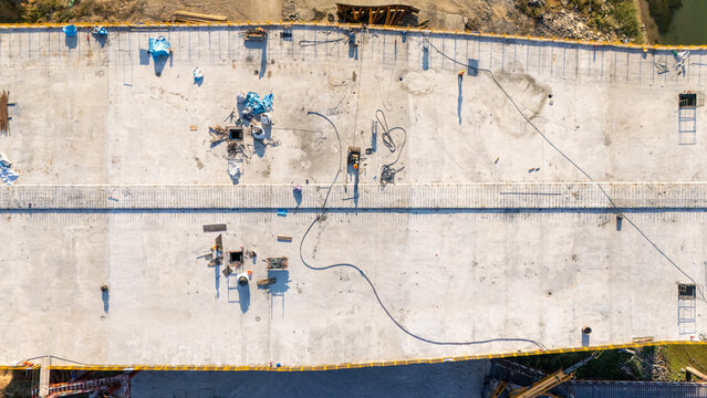 Aerial view of bridge construction site with workers and equipment on concrete surface in Novi Sad, Vojvodina, Serbia.