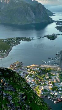 Aerial shot of the ocean meeting the mountains along the beautiful coast of Northern Norway near the town of Reine. Vertical video.