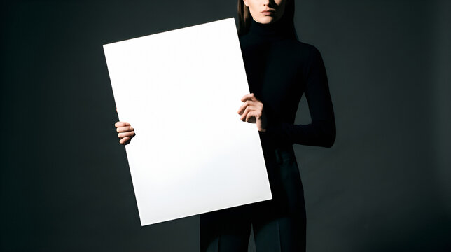Young woman holding blank white sign against dark background