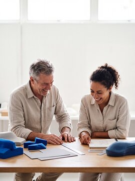 Two cheerful product designers collaborating and laughing together while working on prototypes in a modern bright studio