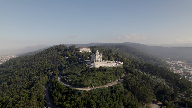 Aerial view of the Sanctuary of the Sacred Heart of Jesus atop a forested hill with winding roads and urban surroundings in Viana do Castelo, Viana do Castelo Dist, Portugal.