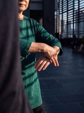 Senior Asian woman practicing mindful Tai Chi hand movements during morning exercise on outdoor terrace