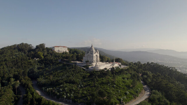 Aerial view of the Sanctuary of the Sacred Heart of Jesus perched on a hill surrounded by dense forest and winding roads in Viana do Castelo, Viana do Castelo Dist, Portugal.