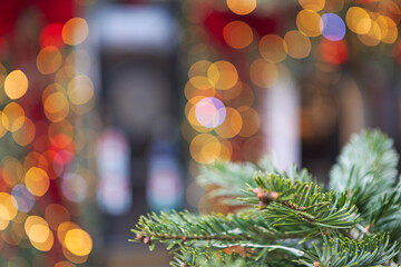 Close-up of fir branch with buds. Blurred golden and red bokeh lights background. Festive winter atmosphere. Christmas decoration. Copy space. New Year's background for greetings © Alla