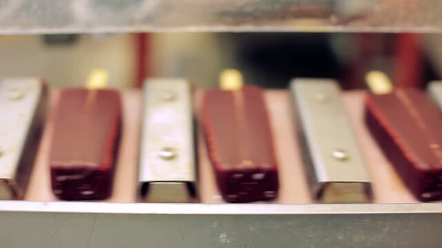 Glazed eskimo bars moving conveyor line. Close up frozen dessert manufacturing.