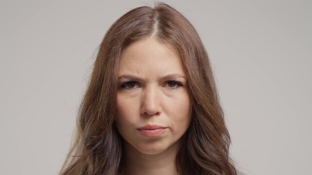 Serious adult woman disapproving with no head sign, nods head disapprovingly. Denying, Rejecting, Disagree, Portrait of pretty lady on white background