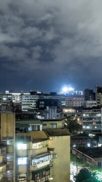 Time Lapse of clouds moving above the buildings of Taipei Taiwan at night. Vertical video.