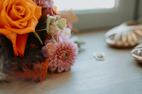Chaussures de mari&eacute;e, bouquet floral et alliances sur une table en bois