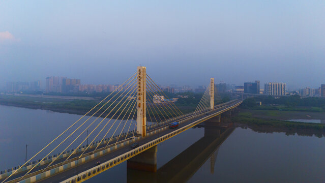 Aerial view of the cable-stayed bridge spanning the Tapi River with the city skyline of Surat in the background under a clear morning sky. Surat, Gujarat, India.
