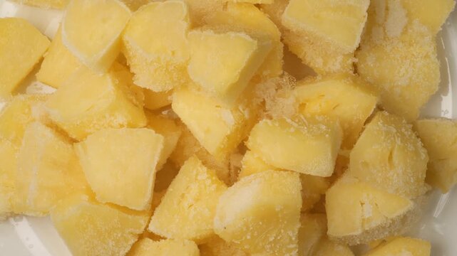 Frozen pineapple chunks rotating on white background