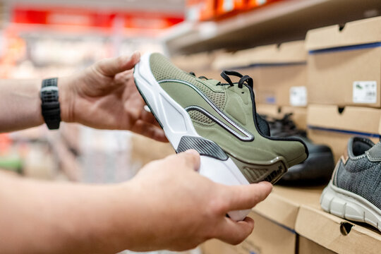 Person holding olive green Puma sneaker