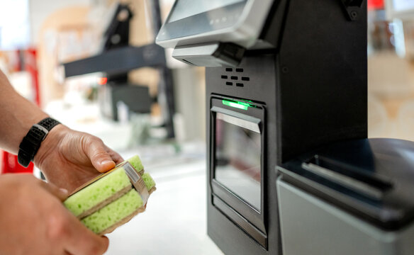 Customer scanning sponge pack at self checkout terminal