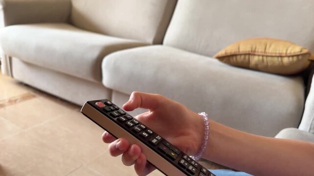 Woman holding television remote control in living room