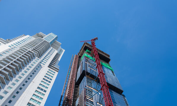 Skyscraper Under Construction with Tower Crane Against Clear Blue Sky