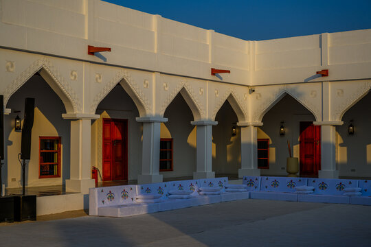 Doha, Qatar - December 13, 2024: Warm afternoon sunlight casts captivating geometric shadows across the facade of the traditional Qatari "Liwan" and white Islamic arches at Darb Al Saai٫