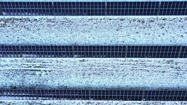 Aerial view of solar panels arranged in rows across a snow-covered field in Latvija.