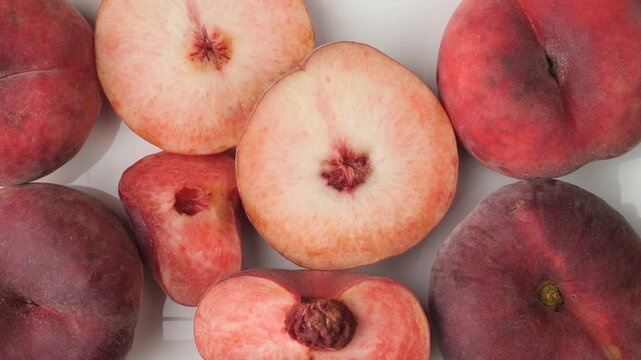 Fresh whole and halved flat peaches isolated on white background