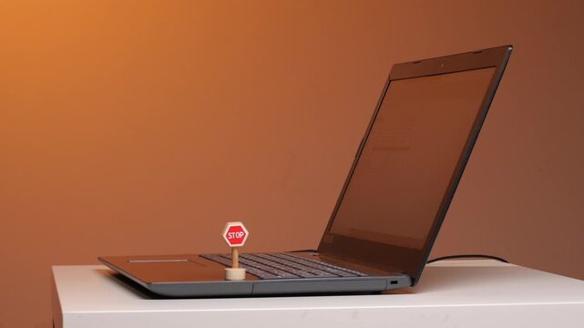 Miniature stop sign resting on a laptop keyboard symbolizing internet censorship, online safety, and digital restriction in the context of cybersecurity and data privacy