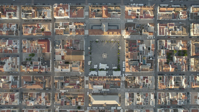 Aerial view of the geometric patterned Praca Marques de Pombal surrounded by historic urban grid and rooftops in Vila Real de Santo Antonio, Faro District, Portugal.