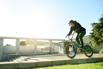 Naklejka premium BMX, man and bicycle in city for cycling, urban challenge and exercise with mockup space. Person, riding bike and cyclist on curb outdoor for fitness, extreme sports or action for balance with cardio