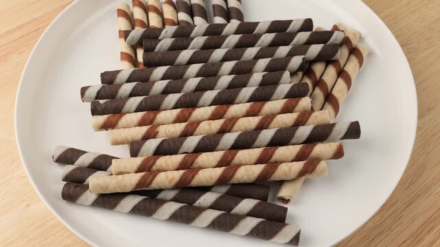 Delicious chocolate rolled wafer sticks rotating on a plate