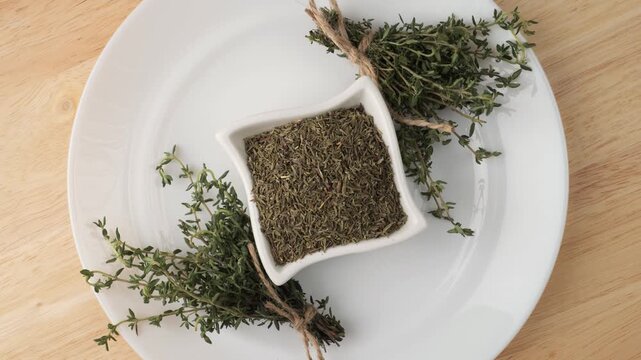 Fresh and dried thyme rotating on a white plate
