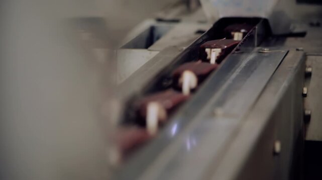 Chocolate popsicles moving stainless steel conveyor closeup. Dessert food plant.